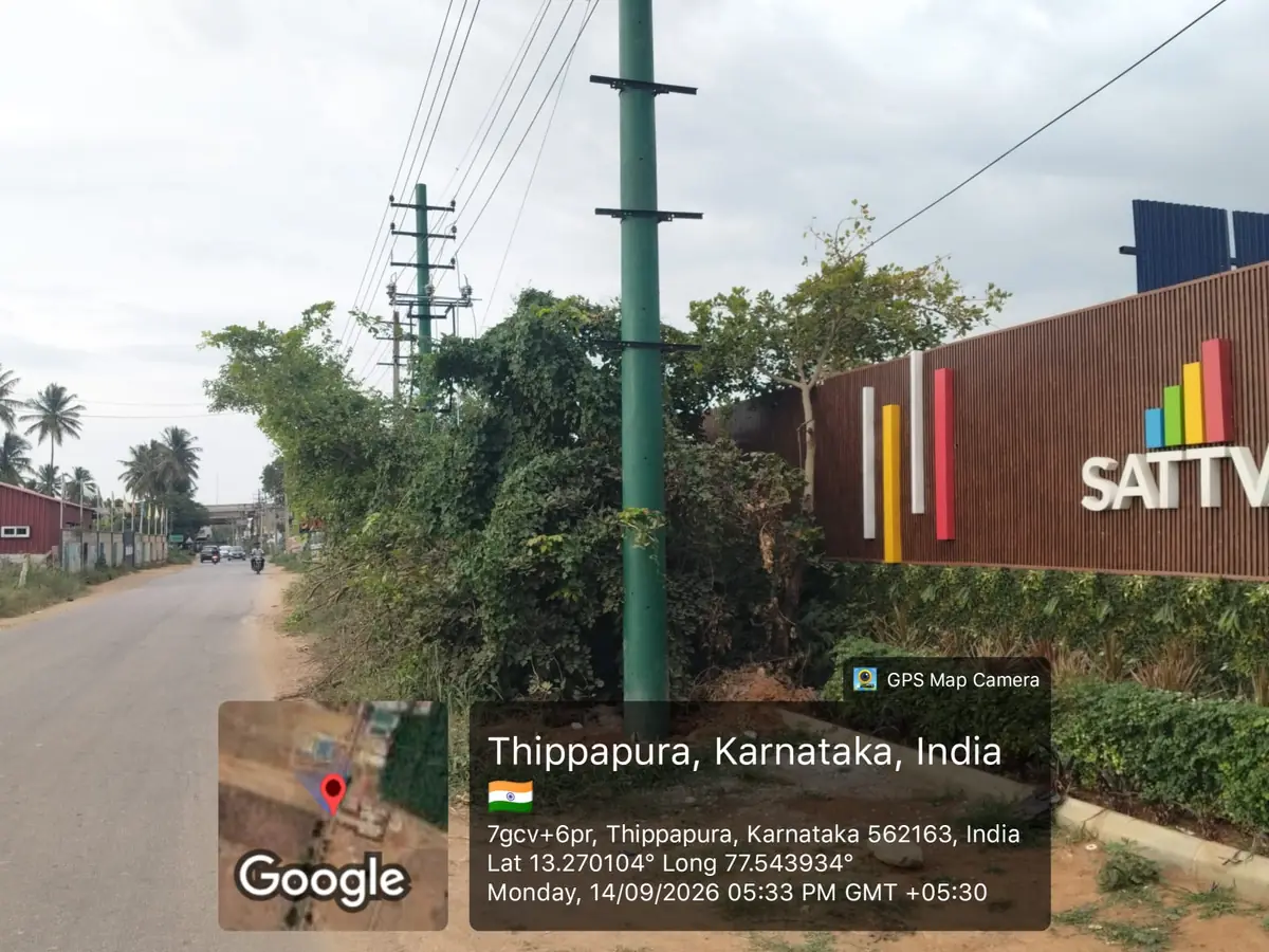 Sattva Ekatra Site Progress 14 September 2026 - Sattva-branded boundary wall with landscaped verge along the approach road, GPS-stamped Thippapura, Doddaballapura